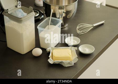 Backteig- oder Tortenzutaten, Mehl, Butter, Ei, Zucker, Backpulver auf grauem Küchentisch Stockfoto