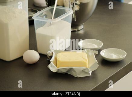 Backteig- oder Tortenzutaten, Mehl, Butter, Ei, Zucker, Backpulver auf grauem Küchentisch Stockfoto