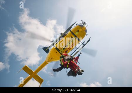 Zwei Sanitäter hängen am Seil unter fliegendem Hubschrauber-Notdienst. Themen Rettung, Hilfe und Helden. Stockfoto