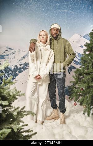 Attraktives Paar, das unter Schnee posiert und stilvolle Winterkleidung, Mode und Stil trägt Stockfoto