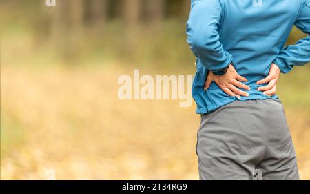 Junger Mann mit einer Sportfigur und einer unteren Rückenverletzung. Rückenschmerzen beim Sport. Stockfoto