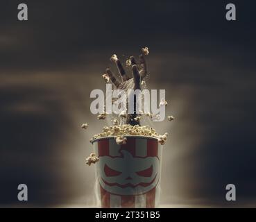 Gruselige Zombie-Hand aus einem vollen Popcorn-Eimer, Horrorfilme und Halloween-Konzept Stockfoto
