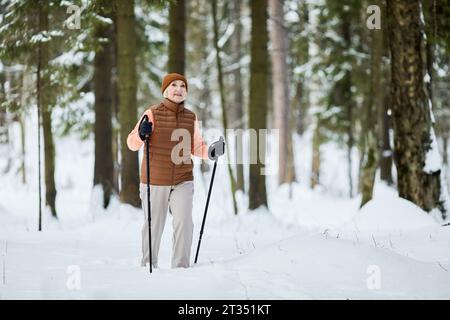 Begeisterte aktive Seniorinnen Trekking durch den wunderschönen Winterwald, genießen Sie die Aussicht und die frische Luft Stockfoto