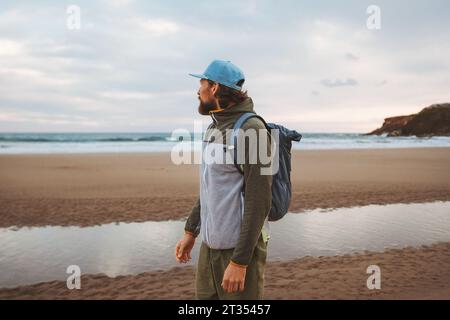 Mann, der alleine am Strand mit Rucksack gesunder Lebensstil aktiv Sommerurlaub Reisende im Freien genießt Meerblick Stockfoto