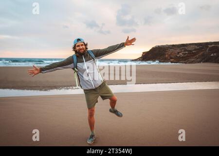 Fröhlicher Mann Tourist im Freien mit Rucksack alleine am Strand zu Fuß Lebensstil aktiver Sommerurlaub Freiheitskonzept Stockfoto