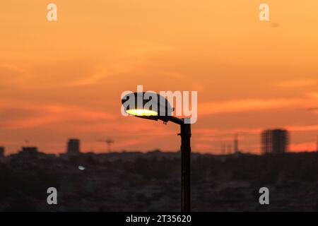 Straßenlaterne vor wunderschönem Sonnenuntergang Himmel, bunten Wolken und Stadtlandschaften. Selektiver Fokus enthalten. Offener Bereich. Stockfoto