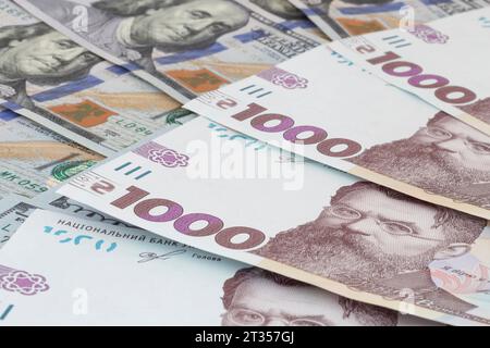 Nahaufnahme mehrerer tausend ukrainischer Hrivnya-Banknoten, die auf US-Dollar-Banknoten liegen Stockfoto