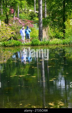 Zwei Menschen spiegelten sich im Magnolia Lake im Himalayan Garden & Sculpture Park in der Nähe von Ripon, North Yorkshire, England Stockfoto