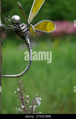 Gelbe geflügelte Dragonfly-Skulptur aus Metall auf Holzpost von Steve Blaylock im Himalaya Garden & Sculpture Park, North Yorkshire, England, Großbritannien. Stockfoto