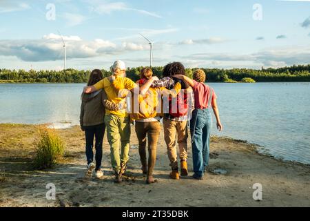 Erleben Sie den Wanderlust-Lebensstil, während eine vielfältige Gruppe junger Freunde, die die Natur genießen, zusammen am Waldsee stehen. Freundschaft und Abenteuer auf dem Display. Freunde umarmen sich am Forest Lake. Hochwertige Fotos Stockfoto