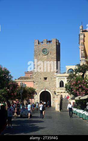 Menschen am steinernen mittelalterlichen Torre dell' Orologio Uhr/Glockenturm in der Porta di Mezzo das Tor zum Dorf Taormina, Sizilien, Italien, EU. Stockfoto