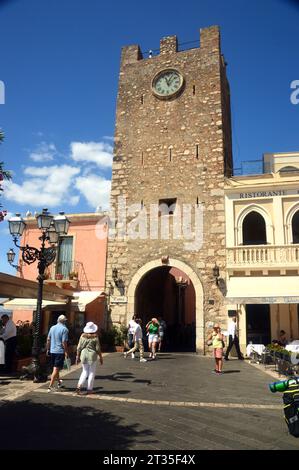 Menschen am steinernen mittelalterlichen Torre dell' Orologio Uhr/Glockenturm in der Porta di Mezzo das Tor zum Dorf Taormina, Sizilien, Italien, EU. Stockfoto