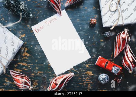 Lieber Weihnachtsmann-Brief, geschrieben mit Buntstiften mit Weihnachtsgeschenken, Ornamenten und Vintage-Spielzeugwagen über rustikalem Hintergrund. Draufsicht von oben. Kopieren Stockfoto