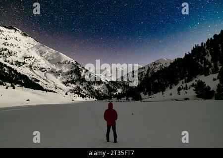 Wanderer, der in einer schneebedeckten Berglandschaft in den Pyrenäen Sternenbeobachtung erlebt Stockfoto
