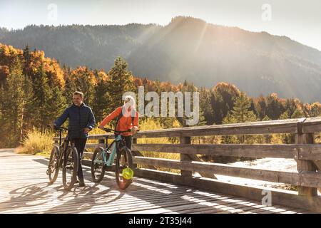 Österreich, Alpen, Paar mit Mountainbikes über eine Brücke Stockfoto