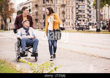 Senior Mann im Rollstuhl, der Zeit mit seinen Enkeln verbringt Stockfoto