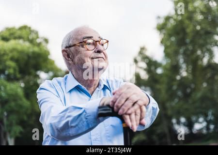 Portrait von älteren Menschen in einem Park lehnte sich auf seinen Gehstock Stockfoto