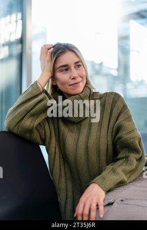 Eine junge Frau, die im Wartebereich sitzt und sich umsieht Stockfoto