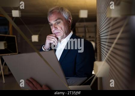 Digitales Composite-Bild eines durchdachten Geschäftsmannes mit Laptop im Büro Stockfoto