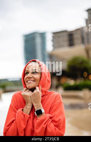 Lächelnde Frau mit Kapuze in der Stadt Stockfoto