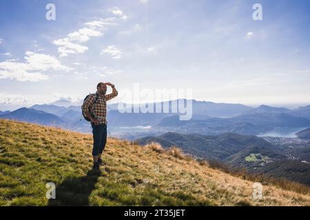 Reifer Mann, der Augen abschirmt, die auf dem Berg stehen Stockfoto