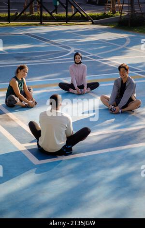 Freunde, die auf dem Sportplatz sitzen und Dehnübungen machen Stockfoto