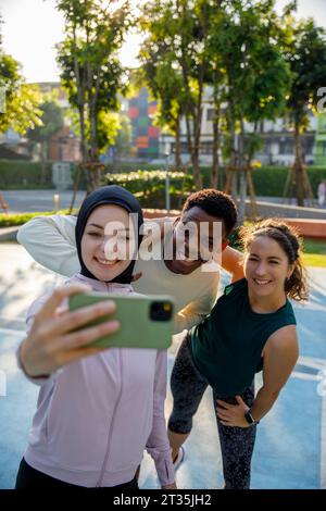 Lächelnde Frau macht Selfie mit Freunden auf dem Sportplatz Stockfoto