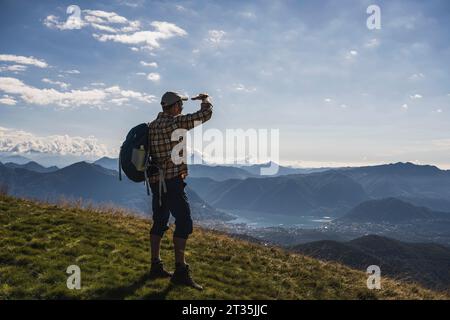 Reifer Wanderer, der Augen abschirmt und auf dem Berg steht Stockfoto