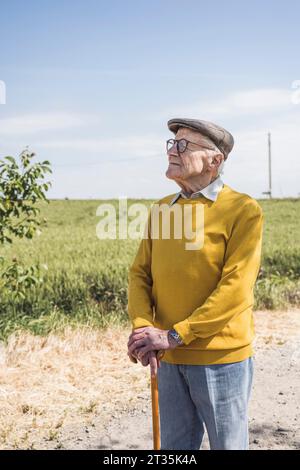 Senior Mann mit Gehstock, der auf dem Feld steht Stockfoto