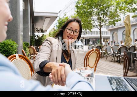 Geschäftspartner beim Handshake am Tisch im Straßencafé Stockfoto