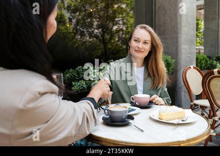 Geschäftspartner beim Handshake mit Kaffeetassen auf dem Tisch im Straßencafé Stockfoto