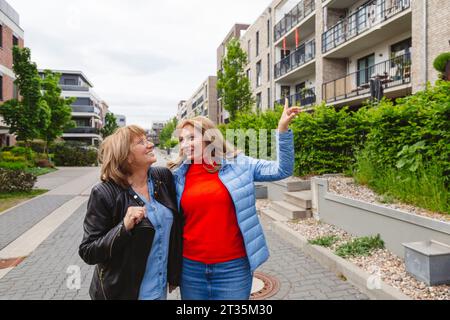 Lächelnde Mutter und Tochter sprechen in der Nähe eines Wohngebietes Stockfoto