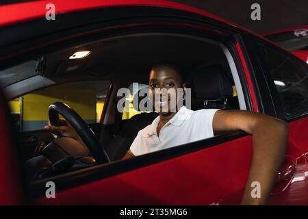 Lächelnde junge Frau sitzt im Auto Stockfoto