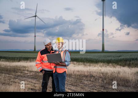 Ingenieure, die an einem Laptop im Windpark arbeiten Stockfoto