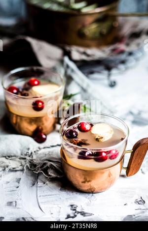 Tassen Moskauer Maultier trinken mit Gewürzen und Preiselbeeren auf dem Tisch Stockfoto