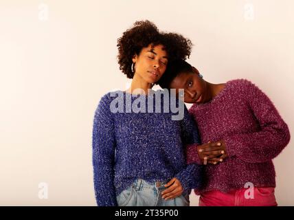Frauen, die sich vor beigefarbenem Hintergrund kopfüber anlehnen Stockfoto
