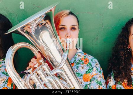 Frau, die Trompete spielt, von Freunden in der Nähe der Mauer Stockfoto