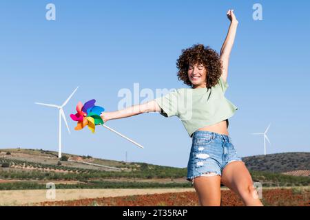 Glückliche Frau, die ein mehrfarbiges Nadelrad-Spielzeug hält Stockfoto