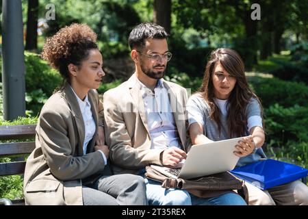 Gruppe von drei jungen Geschäftsleuten für Marketing Telearbeit Finanz- und Strategieexperten, die außerhalb des Bürogebäudes sprechen. Unternehmensmitarbeiter diskutieren Stockfoto