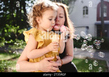 Mutter und Tochter blasen Blasen im Park Stockfoto