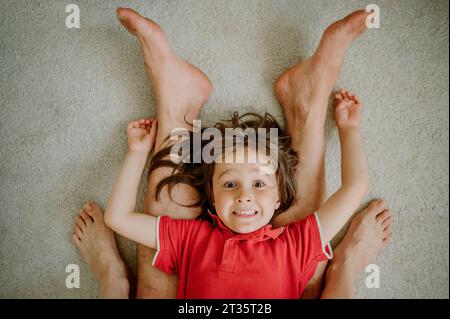 Verspielter Sohn, der Spaß mit den Eltern zu Hause hat Stockfoto