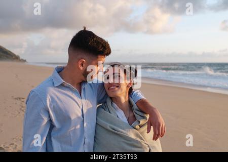 Romantischer Mann mit Arm um Freundin am Strand Stockfoto