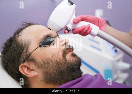 Mann mit Bart, der eine Laserentfernung in der Klinik bekommt Stockfoto