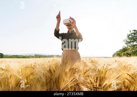 Geschäftsfrau mit Virtual-Reality-Simulator, der inmitten von Ernten steht Stockfoto