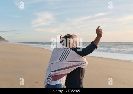 Ältere Frau umarmt Mann am Strand Stockfoto