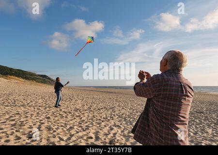 Senior Mann und Frau fliegen Drachen am Strand Stockfoto