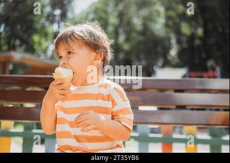 Nachdenklicher Junge, der Eis im Park trinkt Stockfoto