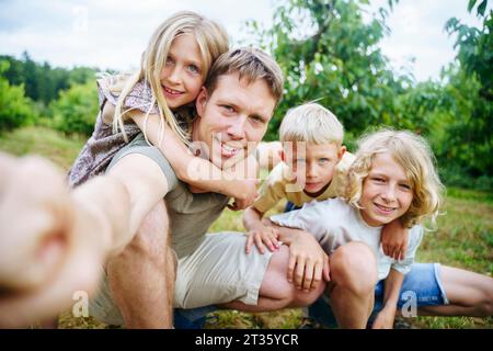 Vater mit Kindern, die Selfie im Garten machen Stockfoto