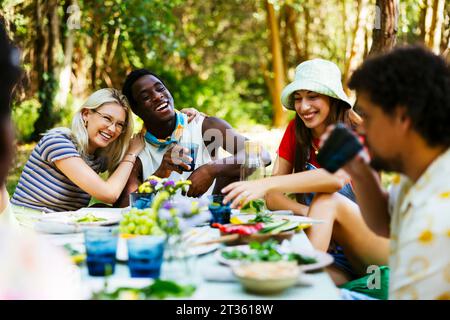 Glückliche Freunde genießen Picknick-Mittagessen im Garten Stockfoto