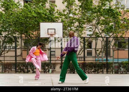 Frau tanzt mit nicht-binärer Person auf dem Basketballfeld Stockfoto